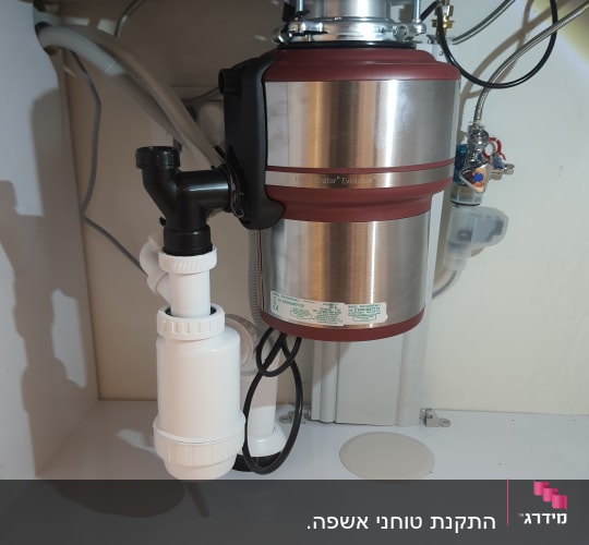 מכשיר טוחן אשפה מתחת לכיור עם צינורות חיבור